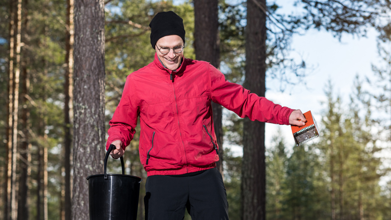 Bussföraren Erik i röd jacka plockar blåbär i skogen.