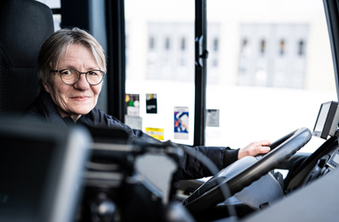 Bussförare Kerstin sittandes bakom ratten i en buss.