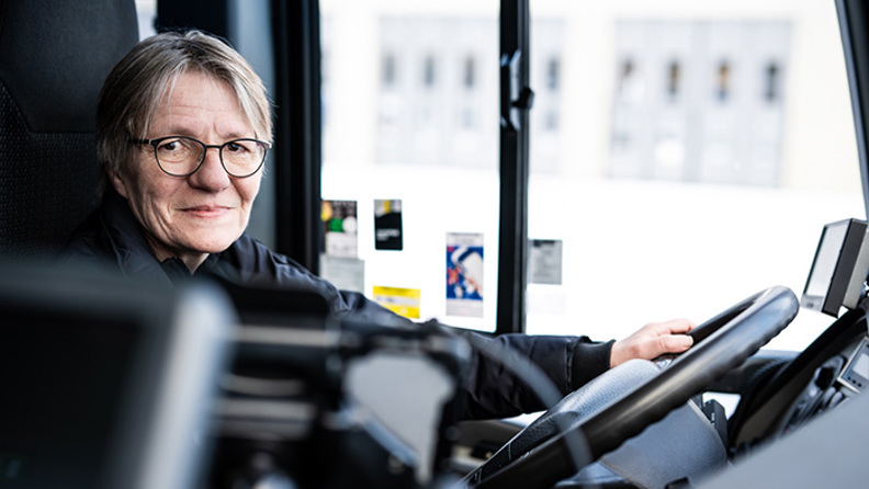 Bussförare Kerstin sittandes bakom ratten i en buss.