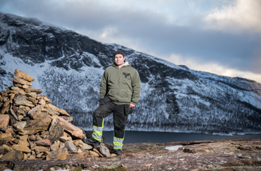 Bussföraren Samuel i varselkläder fotad med en vacker bergsvy i bakgrunden.