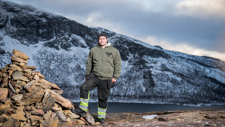 Bussföraren Samuel i varselkläder fotad med en vacker bergsvy i bakgrunden.