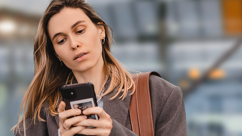 Kvinna tittar i telefonen vid en busstation