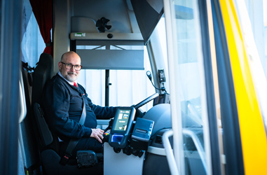Bussförare Nisse sittandes i bussen bakom ratten.