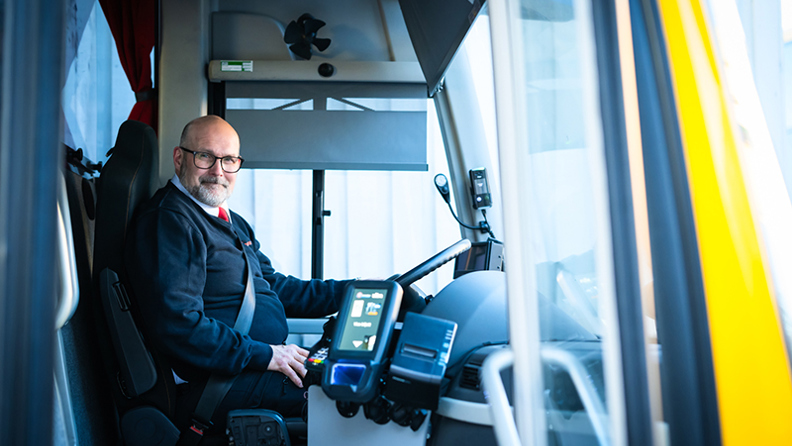 Bussförare Nisse sittandes i bussen bakom ratten.